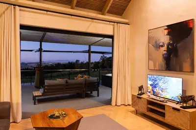 a living room with a couch and a large window at Kunjani Villas & Wines in Stellenbosch