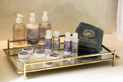 a glass shelf with bottles of soap and a towel at Kunjani Villas & Wines in Stellenbosch