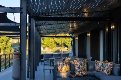 a patio with couches and tables on a balcony at Kunjani Villas & Wines in Stellenbosch