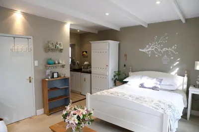 a bedroom with a white bed and a kitchen at The Birdhouse in Cape Town