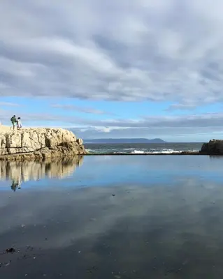 two people standing on the rocks near the water at 7 on Marine in Hermanus