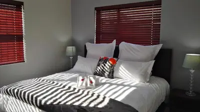 a bedroom with a bed with white sheets and pillows at Bergsig Selfcatering in Gordonʼs Bay