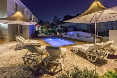 a group of chairs and umbrellas next to a swimming pool at Waterstone Lodge in Somerset West