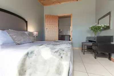 a bedroom with a large bed and a piano at Kingfisher Hollow in Gordonʼs Bay