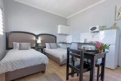 a bedroom with two beds and a desk with a table at Kingfisher Hollow in Gordonʼs Bay