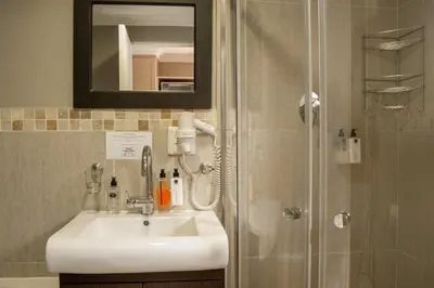 a bathroom with a sink and a shower with a mirror at Ruslamere Hotel and Conference Centre in Durbanville