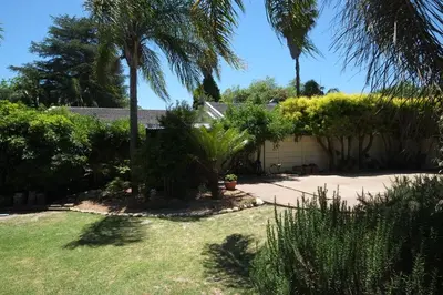 a yard with palm trees and a garage at Eikepark Self Catering in Stellenbosch