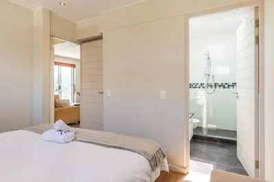 a bedroom with a white bed and a bathroom at da Heim Guest House in Cape Town