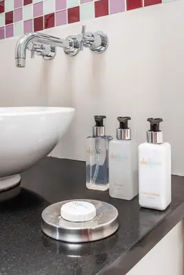 a bathroom with three bottles of soap and a sink at da Heim Guest House in Cape Town