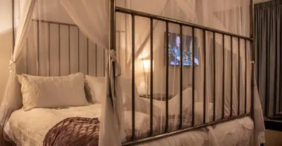 a bedroom with a crib with white pillows at Fijnbos Manor in Bettyʼs Bay