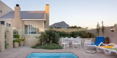 a patio with a table and chairs and a pool at Fijnbos Manor in Bettyʼs Bay