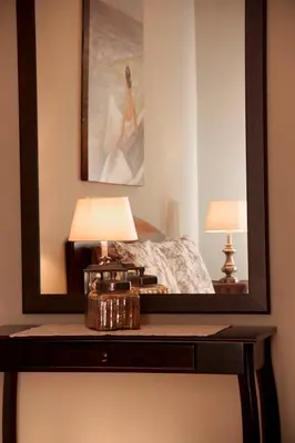 a mirror on a table with a bed and two lamps at A Smart Stay Apartments in Somerset West