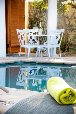 a swimming pool with a table and chairs and a pool toy at A Smart Stay Apartments in Somerset West