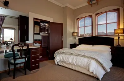 a bedroom with a bed and a desk and a sink at A Smart Stay Apartments in Somerset West