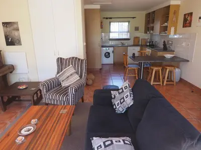 a living room with a couch and a kitchen at Swallow's Nest in Somerset West