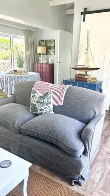 a gray couch in a living room with a table at Kallistes Misty Shores Cottage in Bettyʼs Bay