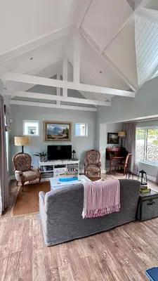 a living room with a large bed and a couch at Kallistes Misty Shores Cottage in Bettyʼs Bay