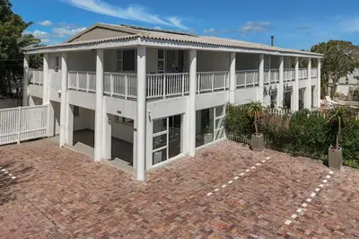 a large white building with a porch at Oude Schuur Boutique Guesthouse in Hermanus