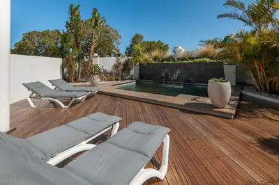 a deck with lounge chairs and a swimming pool at Oude Schuur Boutique Guesthouse in Hermanus