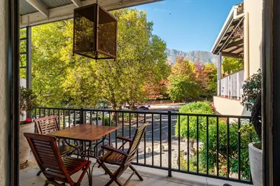 a patio with a table and chairs on a balcony at The Ivy Apartments Franschhoek in Franschhoek