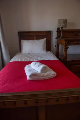 a white towel laying on a red bed at Windfall Wine Farm in Robertson