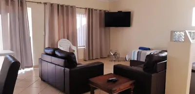 a living room with two chairs and a bed at Getaway Self-Catering Tyger Valley in Durbanville