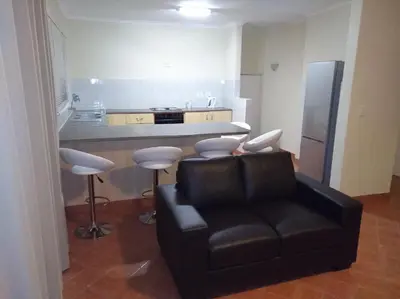 a living room with a leather chair and a kitchen at Getaway Self-Catering Tyger Valley in Durbanville