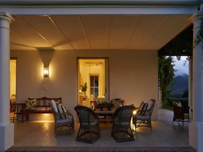 a living room with a table and chairs on a patio at La Cotte House in Franschhoek