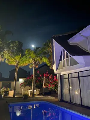 a house with a swimming pool at night at Southern Cross Guesthouse in Somerset West