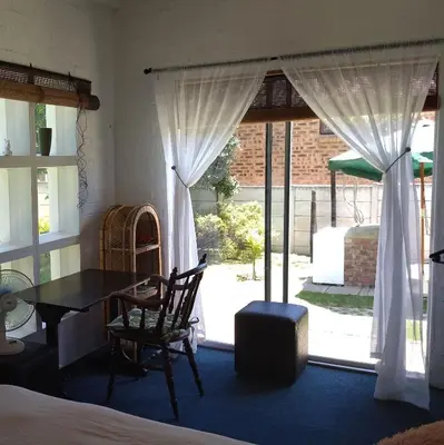 a room with a bed and a table and a window at Festina Lente in Onrus in Hermanus