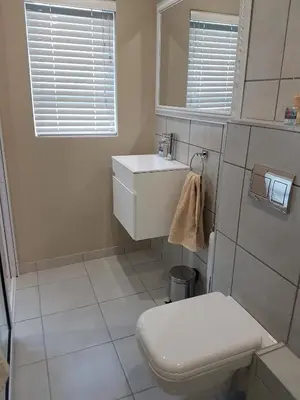 a white bathroom with a toilet and a sink at Studio on Bourdeaux in Panorama