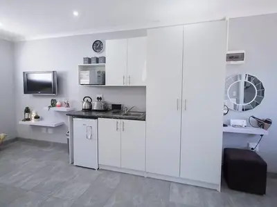 a kitchen with white cabinets and a black counter top at Studio on Bourdeaux in Panorama