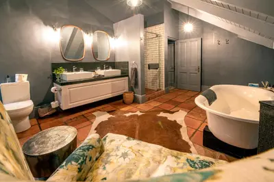 a bathroom with a tub and a sink and a toilet at Avondrood Guest House by The Oyster Collection in Franschhoek