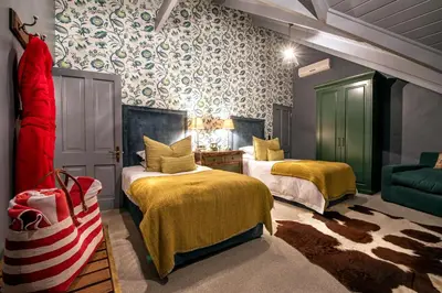 a room with two beds and a couch in it at Avondrood Guest House by The Oyster Collection in Franschhoek