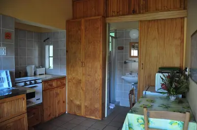 a kitchen with wooden cabinets and a table and a sink at Kierie Kwaak Self Catering in Stellenbosch