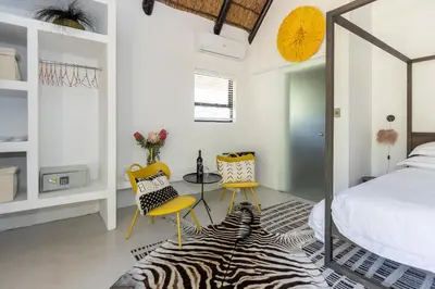 a bedroom with a bed and two yellow chairs at Africa Lodge in Somerset West