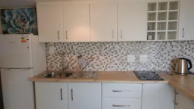 a kitchen with white cabinets and a sink at Agape Apartments in Somerset West