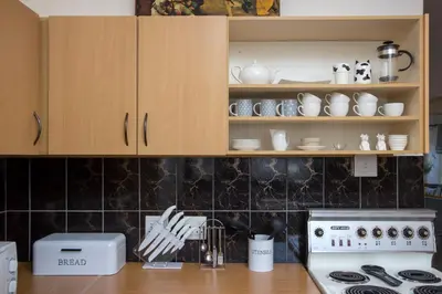 a kitchen with a stove and cabinets with dishes at Stone Chimney Cottage in Hermanus
