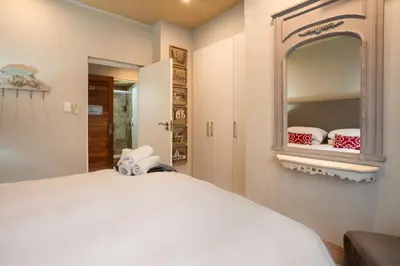a bedroom with a large white bed and a mirror at Avemore Eikehoff No 23 - full Backup Power in Stellenbosch