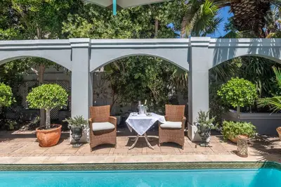 a patio with a table and chairs next to a pool at Maison du Cap in Cape Town