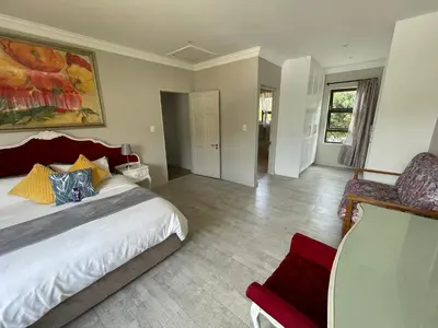 a bedroom with a large bed and a chair at Bird's View Guest Accommodation in Hermanus