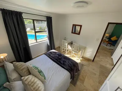 a bedroom with a bed and a view of a pool at Bird's View Guest Accommodation in Hermanus