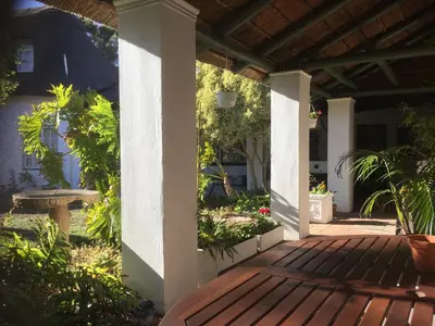 a porch with a wooden deck with a table and plants at Howards End Manor B&B in Cape Town