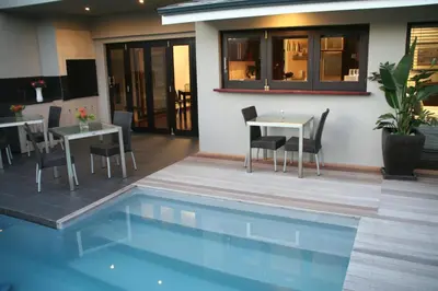 a patio with a table and chairs next to a pool at Keren's Vine Guesthouse in Stellenbosch