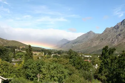 a rainbow over a valley with mountains in the background at Keren's Vine Guesthouse in Stellenbosch