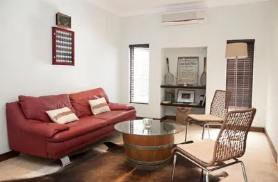 a living room with a red couch and a table at Keren's Vine Guesthouse in Stellenbosch
