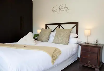 a bedroom with a white bed and a wooden nightstand at Keren's Vine Guesthouse in Stellenbosch