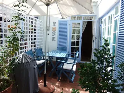 a patio with a table and chairs and an umbrella at Eastbury Cottage in Hermanus
