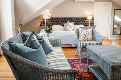 a bedroom with a bed and chairs and a couch at Auberge Clermont in Franschhoek