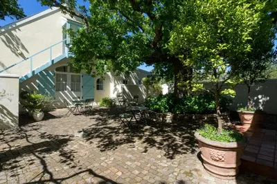 a patio with chairs and a tree in front of a building at Auberge Clermont in Franschhoek